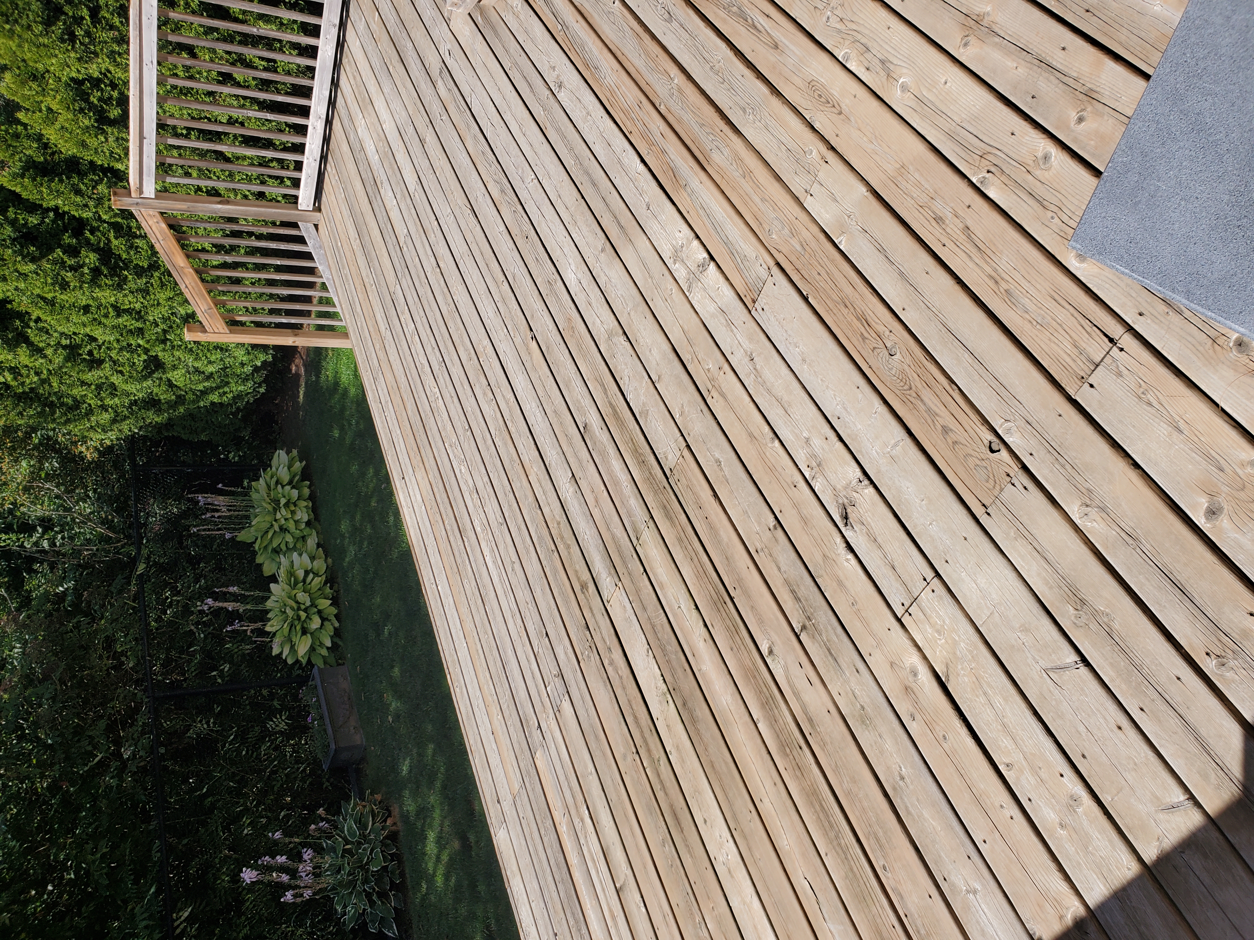 Deck before restoration — pressure washed bare grey boards, wood railing