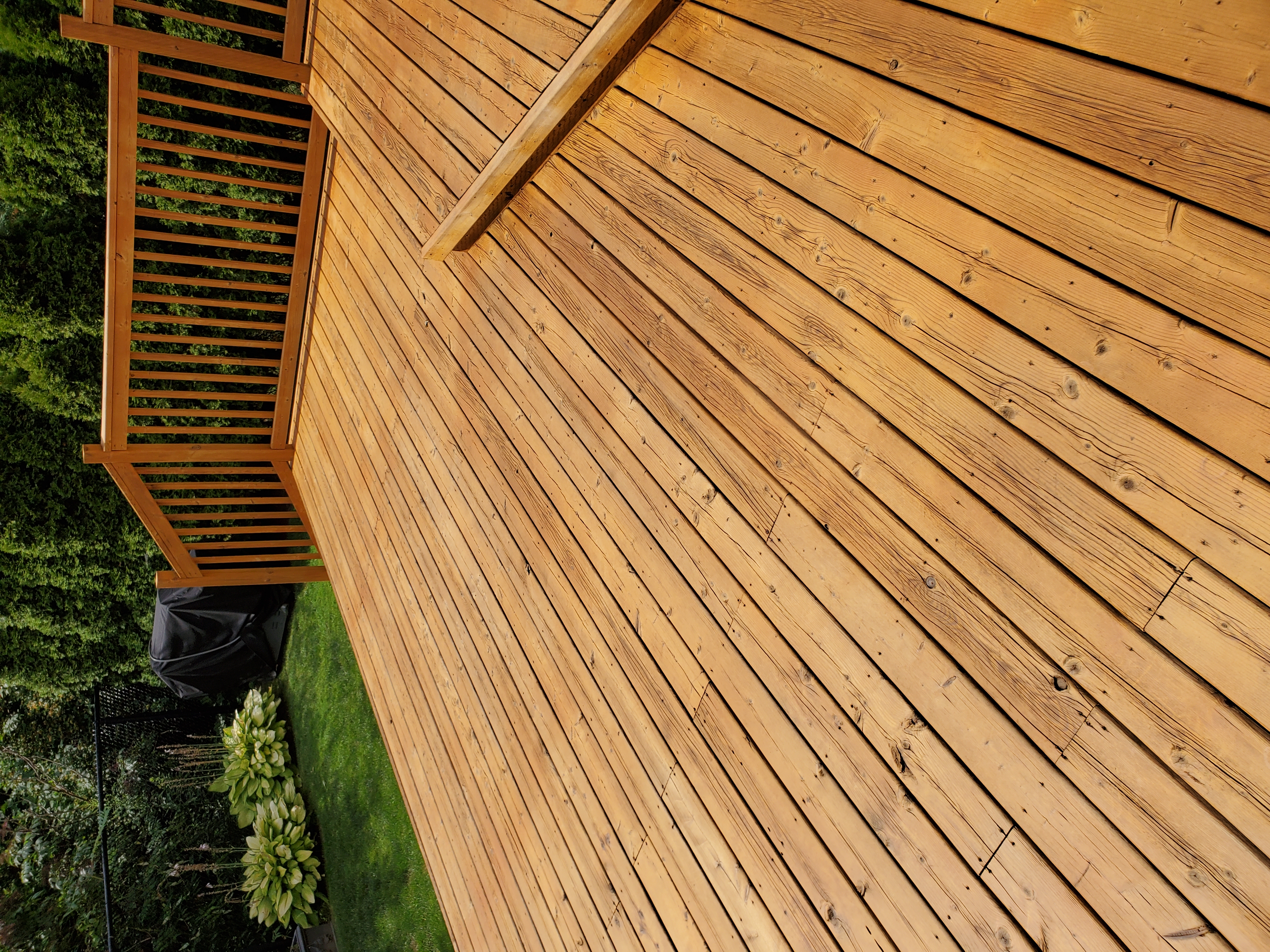 Same deck after 2-coat stain — rich honey gold boards, same railing