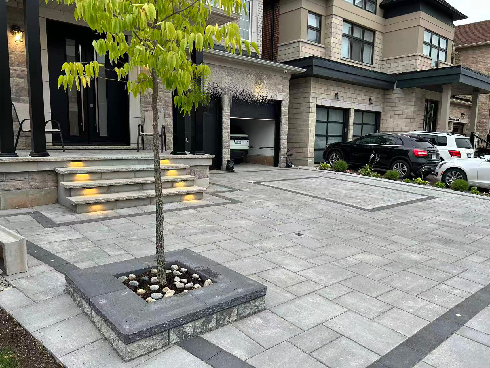 Completed luxury front driveway interlock with built-in tree planter and lit steps — GTA