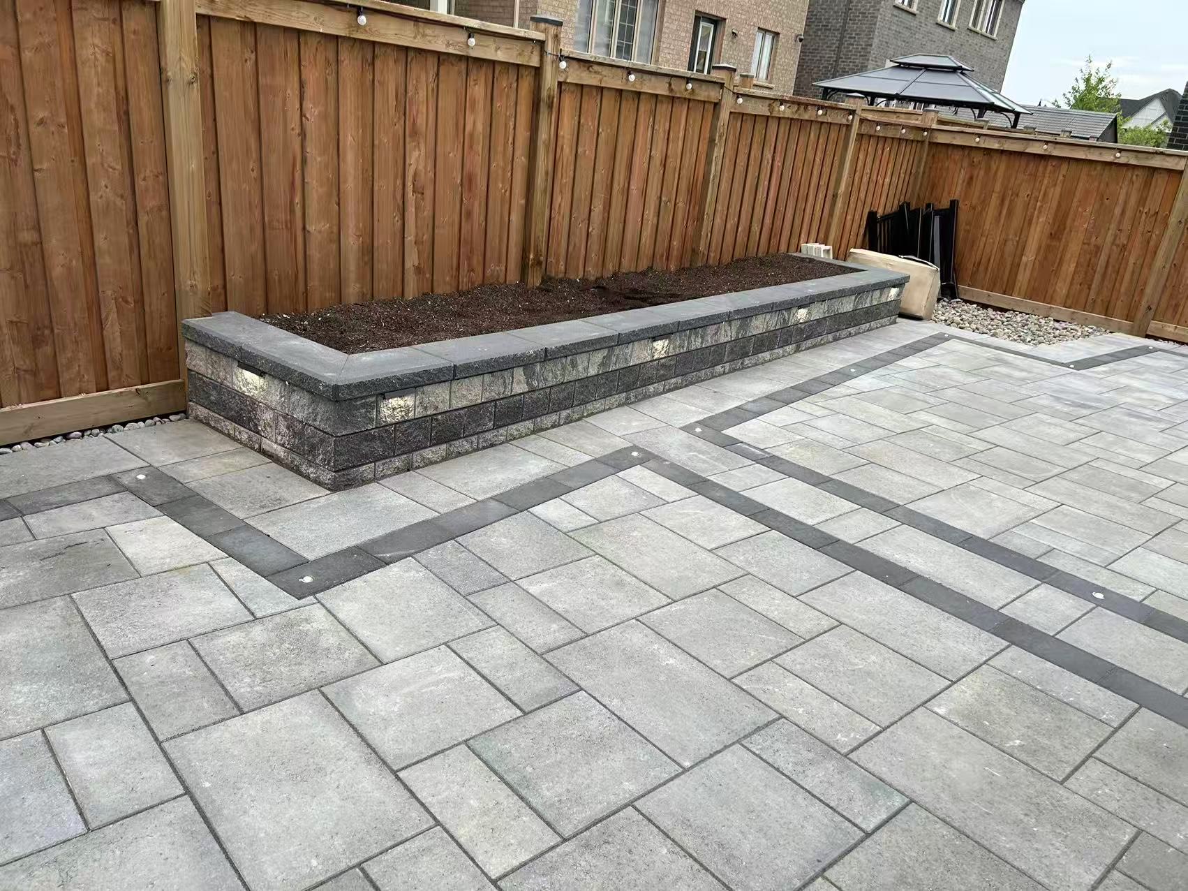 Cedar privacy fence as backdrop to completed interlock patio with raised garden bed