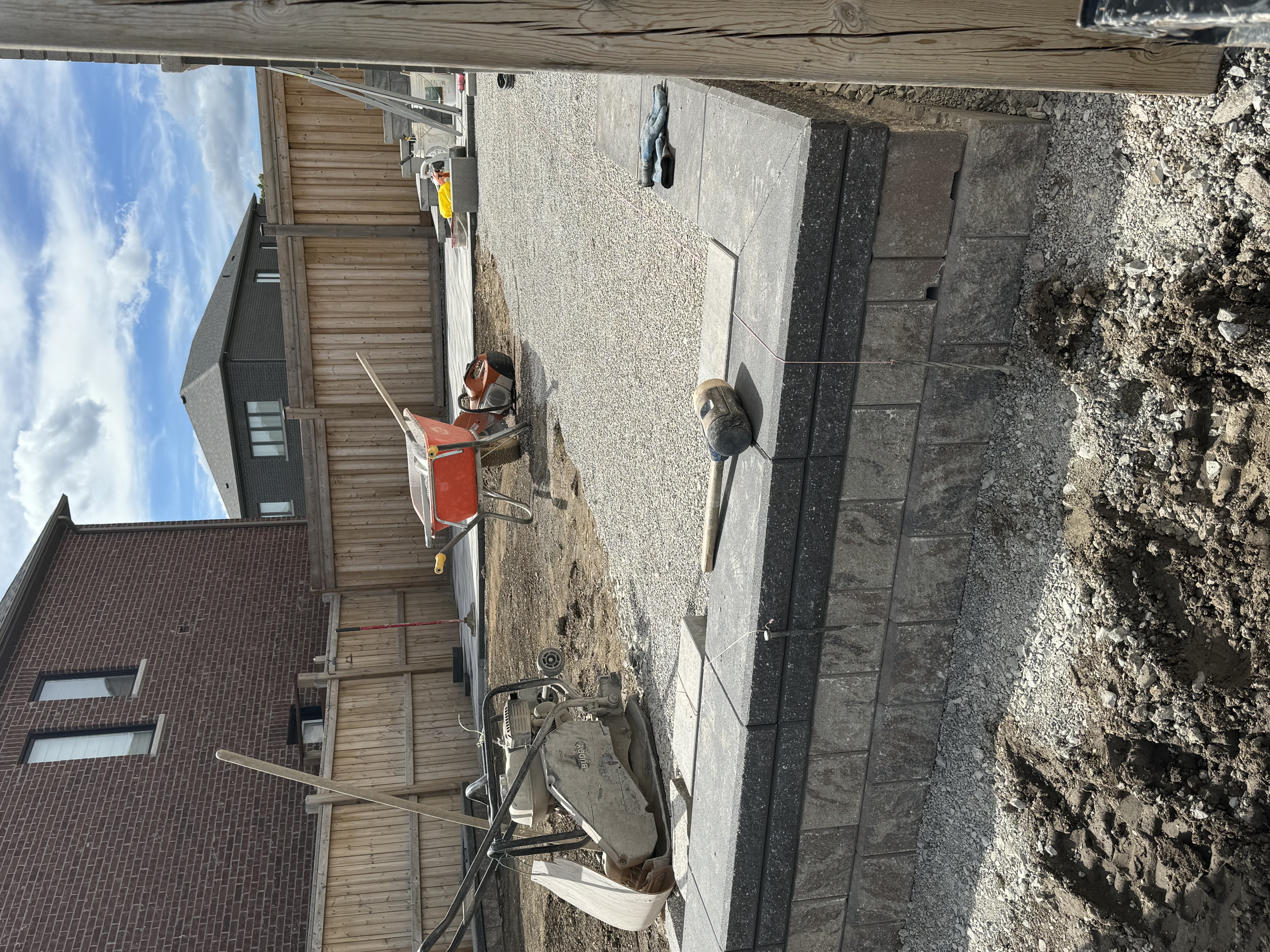 Backyard interlock installation in progress — retaining wall and gravel base