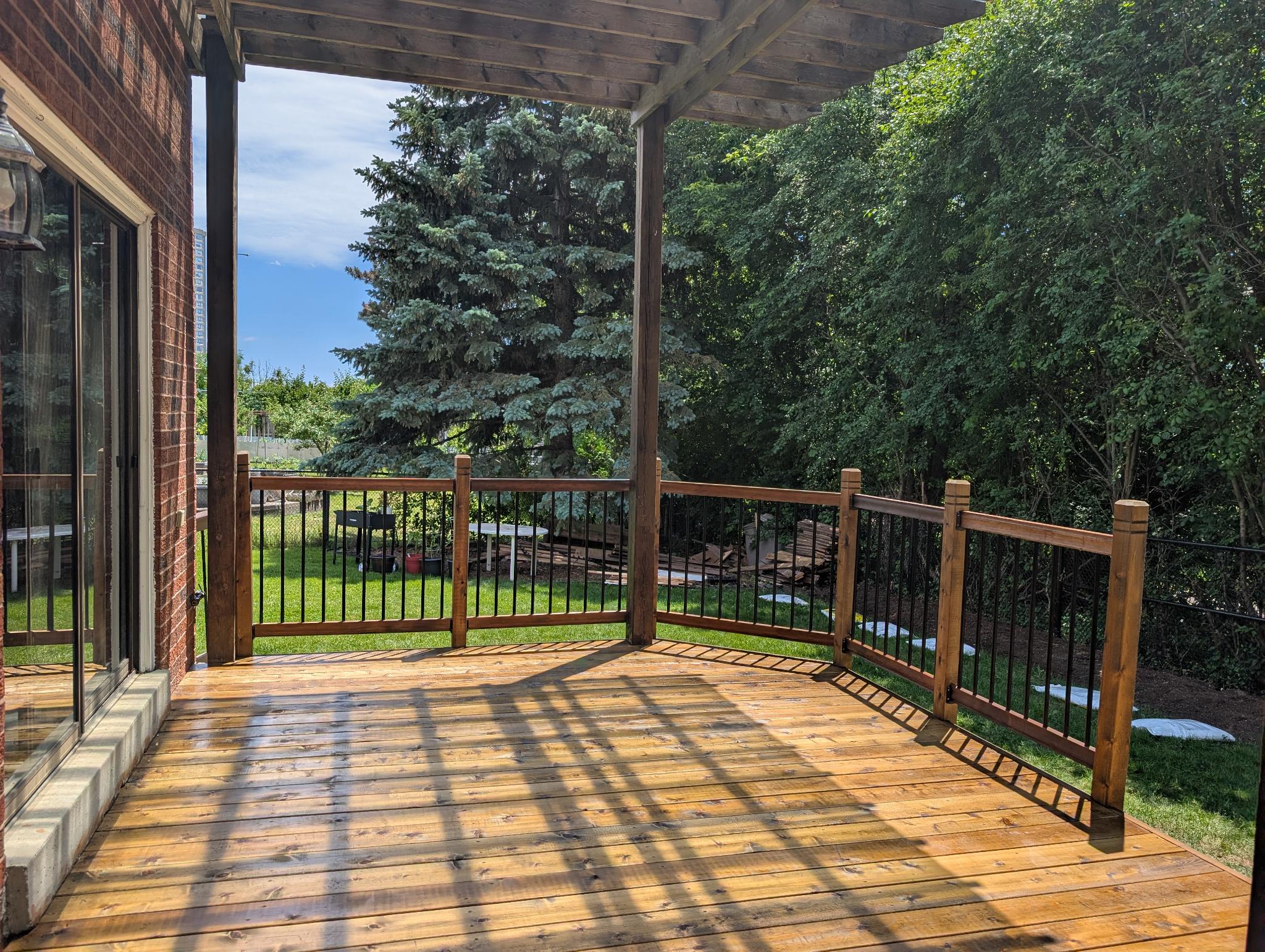 Completed stained deck with pergola and black metal balusters
