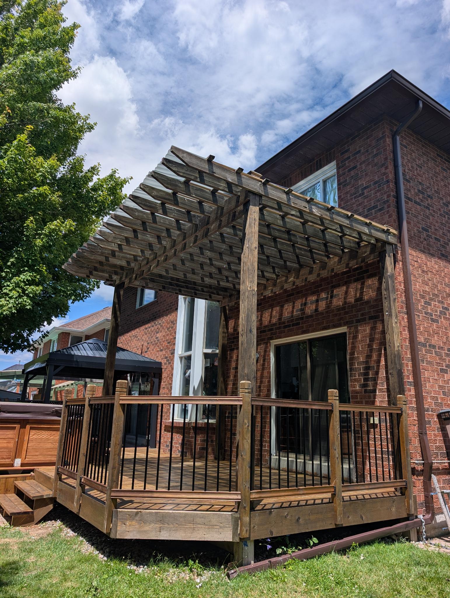 Deck with wood pergola before — weathered grey boards and structure, brick home